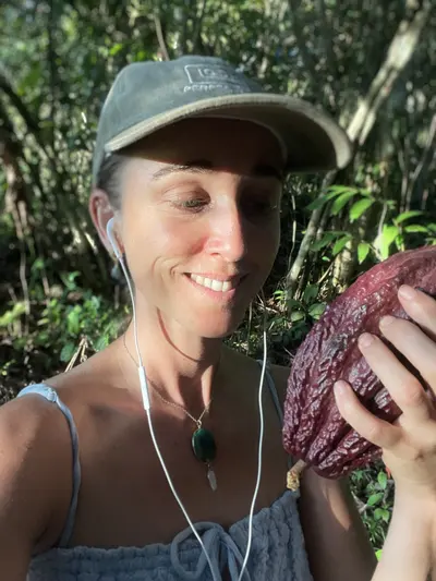 Clari García González sosteniendo un fruto de cacao en la selva