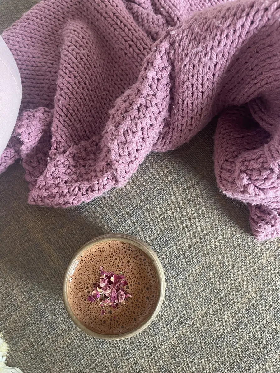 Taza de cacao ceremonial con pétalos de rosa sobre una manta
