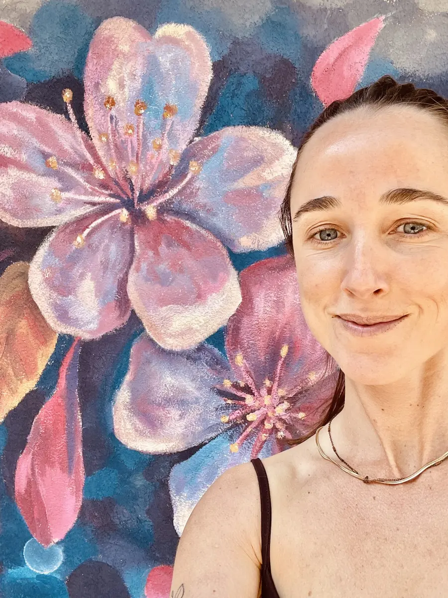 Selfie de Clari García González frente a un mural de flores
