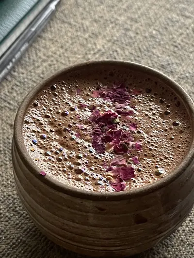 Taza de cacao ceremonial con pétalos de rosa en primer plano