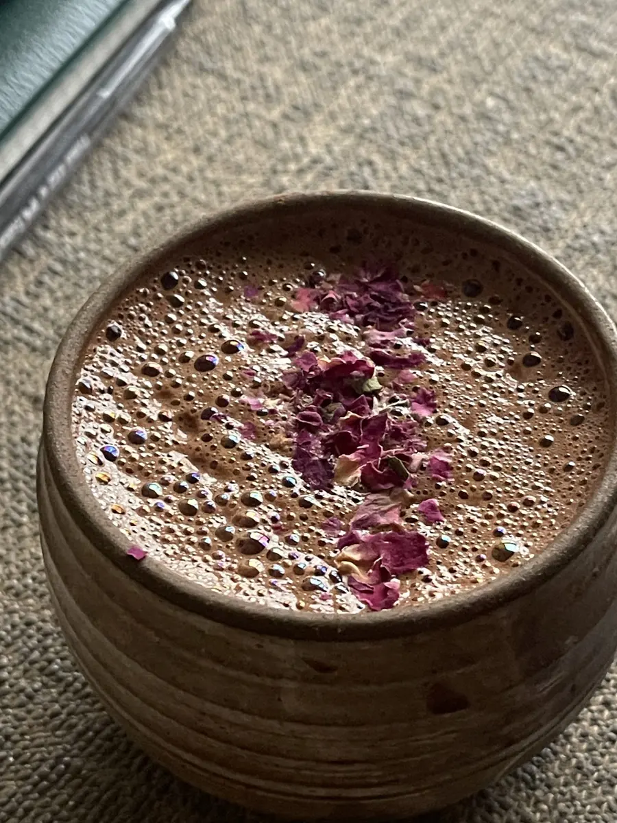 Taza de cacao ceremonial con pétalos de rosa en primer plano
