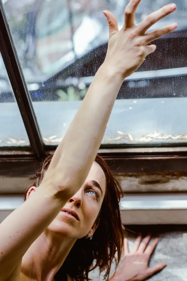 Clari García González en una postura de yoga con un brazo extendido hacia la luz de una ventana